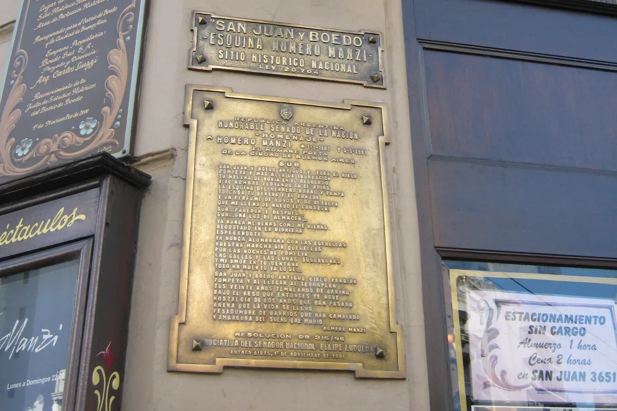 Placas de bronce en la esquina de Esquina Homero Manzi, una que marca la esquina como Sitio Histórico Nacional y otra más grande en homenaje a Homero Manzi, junto a un cartel de madera pintado y un farol de hierro