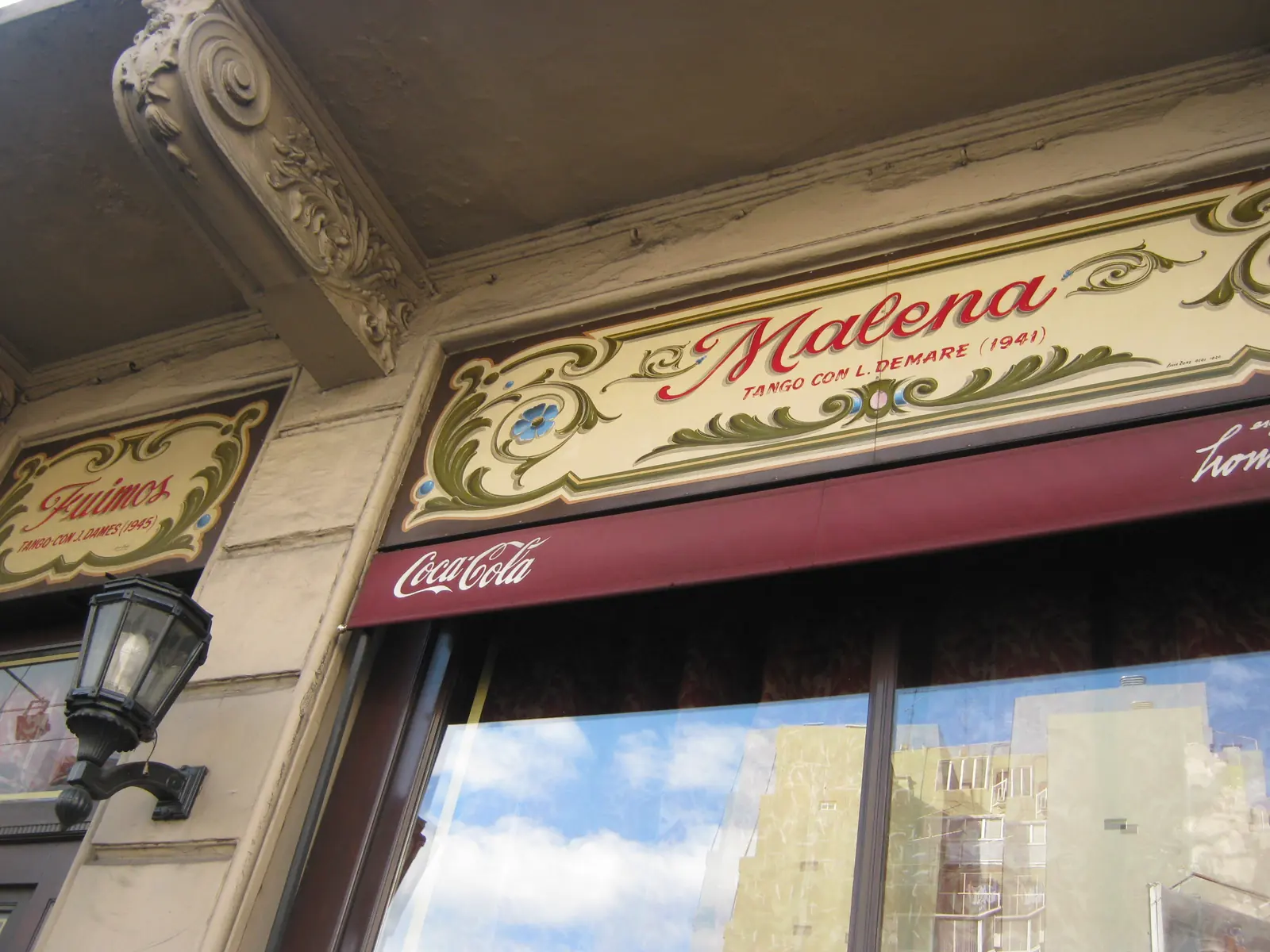 Un'insegna dipinta in stile fileteado sopra una finestra dell'Esquina Homero Manzi che intitola il tango Malena, con il compositore e l'anno in piccole lettere sotto il titolo